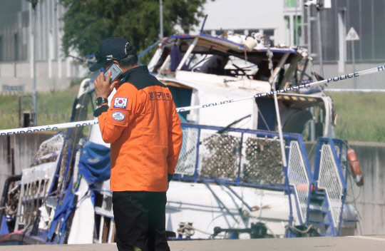 12일(현지시간) 전날 인양된 허블레아니호가 정밀 수색 및 조사를 위해 정박하고 있는 헝가리 부다페스트 다뉴브강 체펠섬 코파시갓 선착장 c1 도크에서 우리 정부 신속대응팀 관계자가 헝가리 측 관계자들을 기다리며 허블레아니호 앞에서 통화를 하고 있다.  연합뉴스
